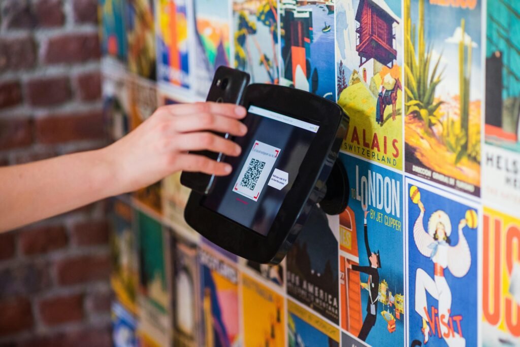 A hand scanning a QR code with a smartphone on a wall covered in vibrant posters indoors.