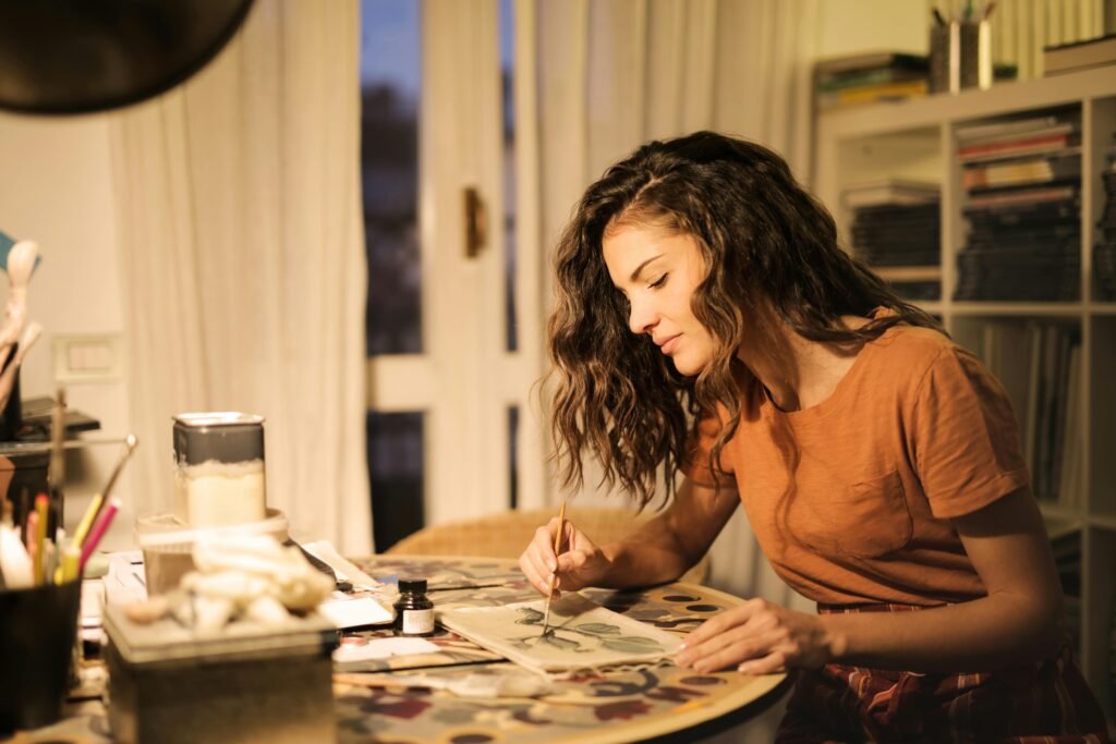 A young woman artist concentrating on a painting project inside her studio.