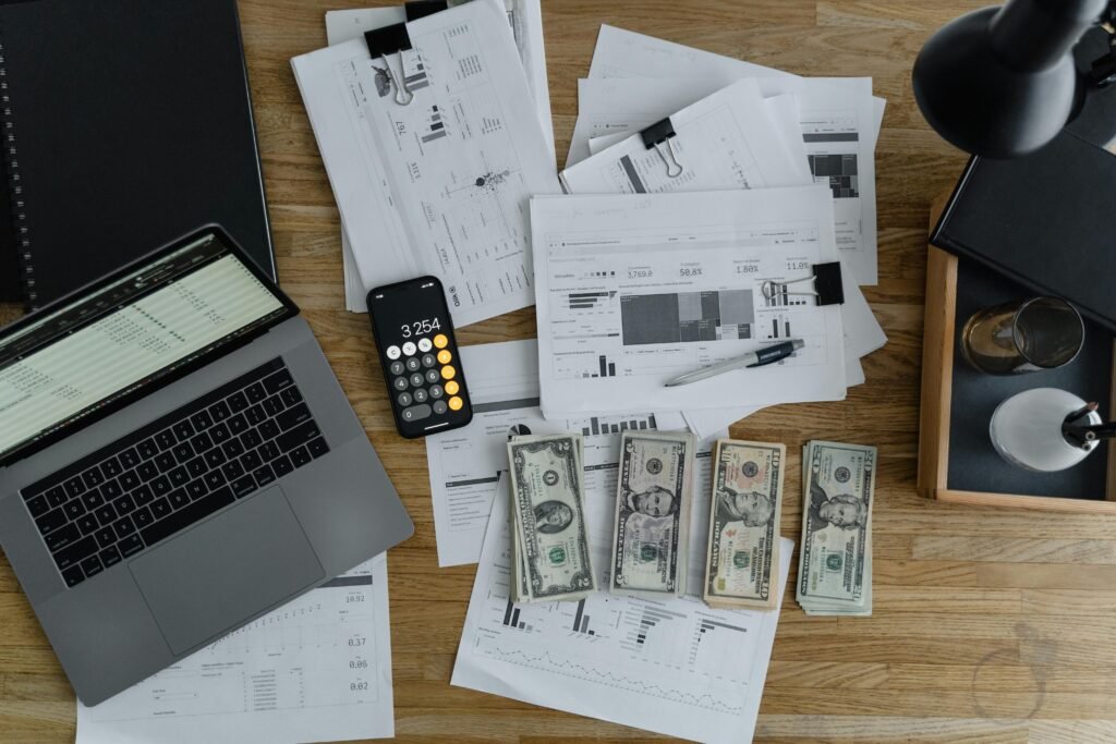 pexels-photo-6693655-6693655 Overhead view of financial documents, cash, and technology on a wooden desk.